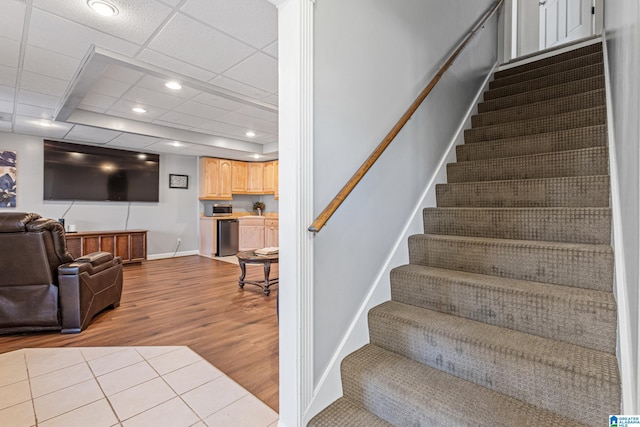 stairway featuring a drop ceiling and wood-type flooring