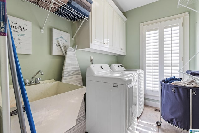 laundry area with cabinets, light tile patterned floors, sink, and washing machine and clothes dryer