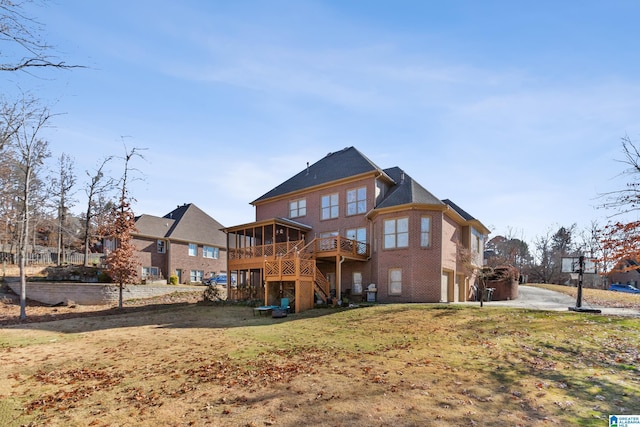 back of house featuring a sunroom, a garage, a yard, and a deck