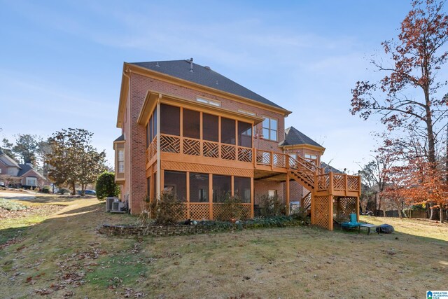 rear view of property featuring a lawn, a sunroom, cooling unit, and a wooden deck