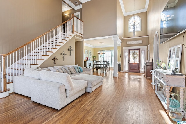 living room featuring a high ceiling, hardwood / wood-style flooring, an inviting chandelier, and ornamental molding