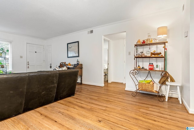 living room featuring ornamental molding and light wood-type flooring