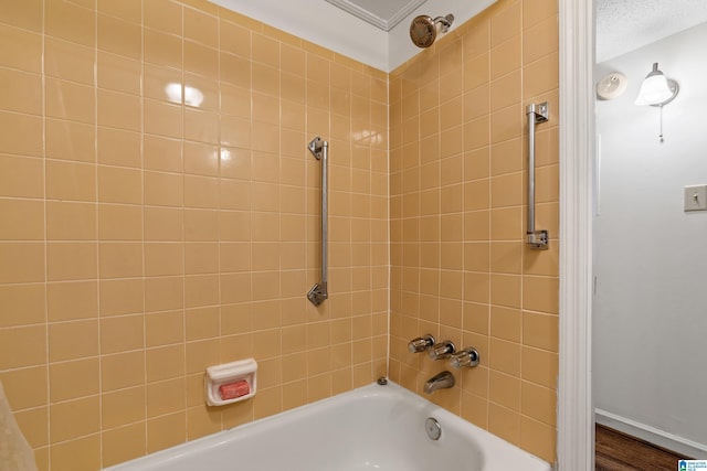 bathroom featuring a textured ceiling and tiled shower / bath