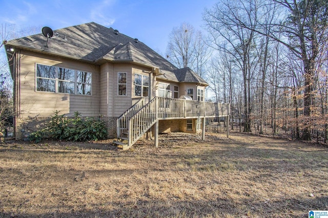 rear view of property featuring a shingled roof, stairway, a wooden deck, and a yard