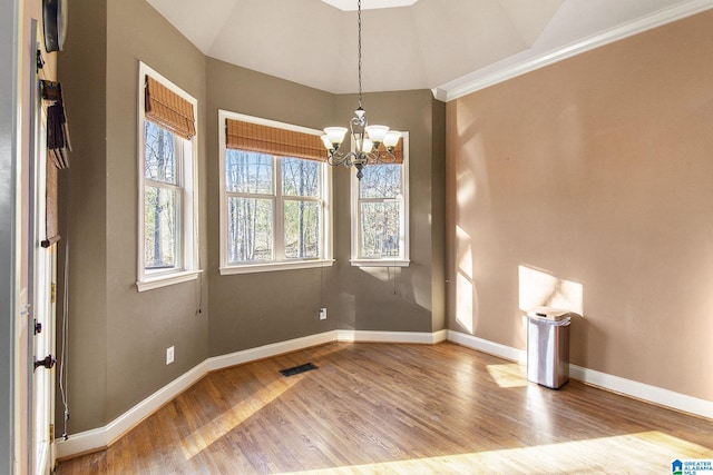 unfurnished dining area featuring vaulted ceiling, light hardwood / wood-style flooring, an inviting chandelier, and crown molding