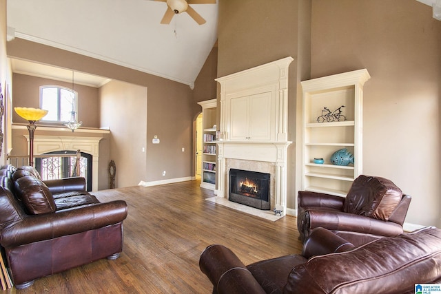 living room featuring ceiling fan, crown molding, a fireplace, a high ceiling, and dark hardwood / wood-style floors