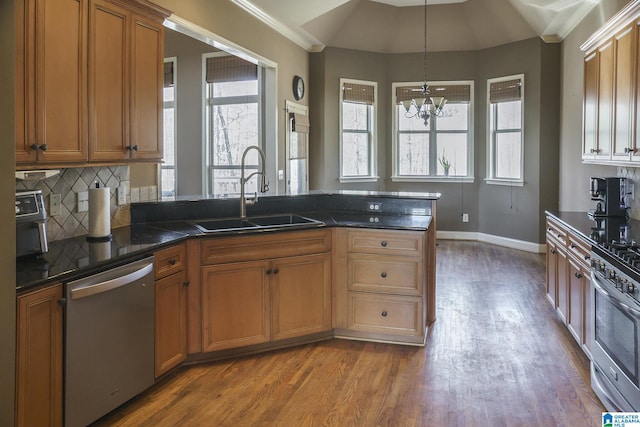 kitchen with tasteful backsplash, decorative light fixtures, stainless steel appliances, light wood-style floors, and a sink