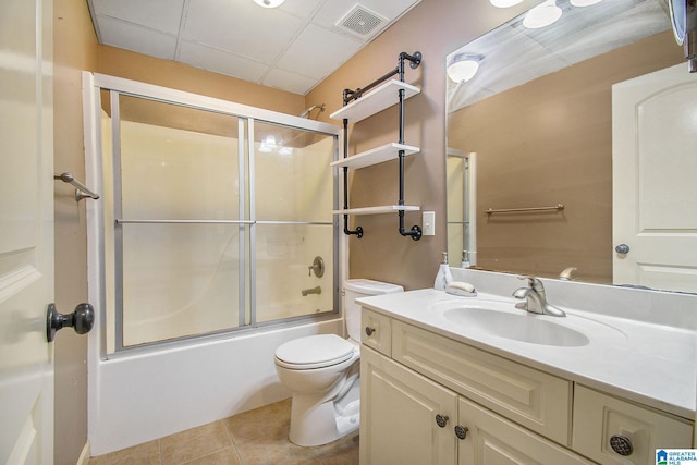 full bathroom featuring tile patterned flooring, combined bath / shower with glass door, toilet, a paneled ceiling, and vanity