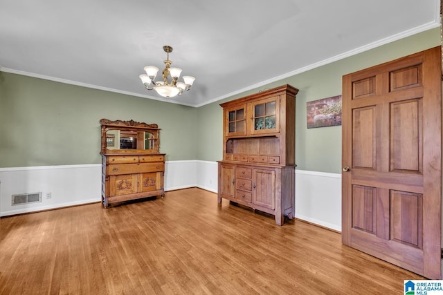 dining area with light hardwood / wood-style floors, an inviting chandelier, and crown molding