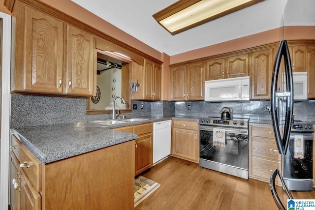 kitchen featuring light wood-type flooring, white appliances, tasteful backsplash, and sink