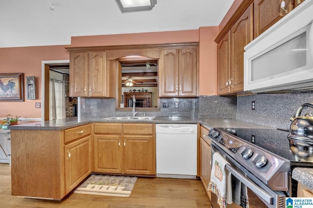 kitchen with sink, light hardwood / wood-style flooring, kitchen peninsula, white appliances, and decorative backsplash