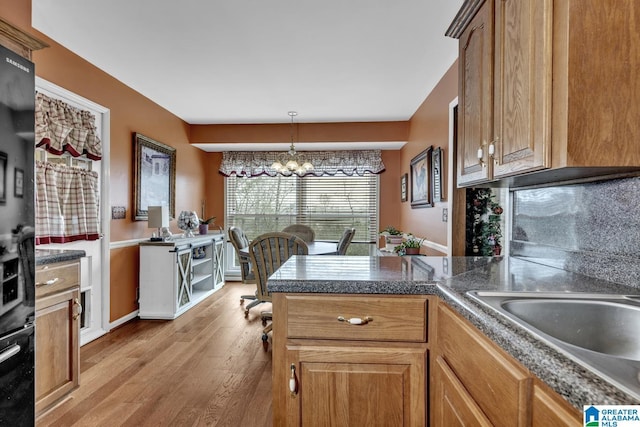 kitchen featuring pendant lighting, a notable chandelier, light wood-type flooring, and sink