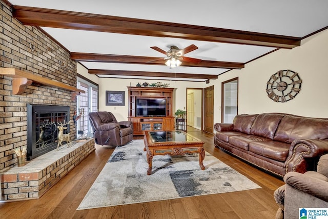 living room with a fireplace, wood-type flooring, ceiling fan, and beamed ceiling