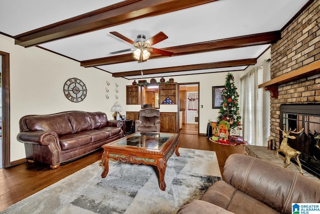 living room featuring beamed ceiling, a brick fireplace, ceiling fan, and dark wood-type flooring