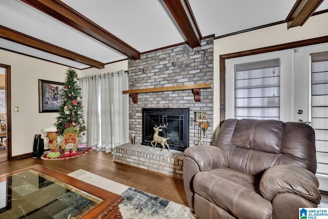 living room with beam ceiling, a brick fireplace, crown molding, and hardwood / wood-style flooring