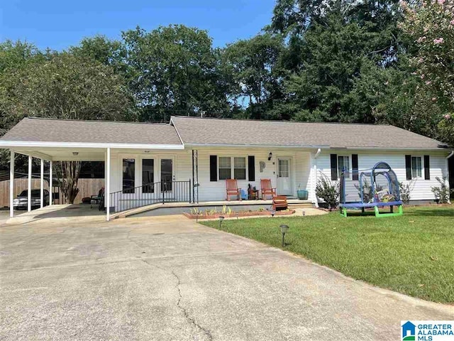 single story home with a carport, a porch, a trampoline, and a front lawn