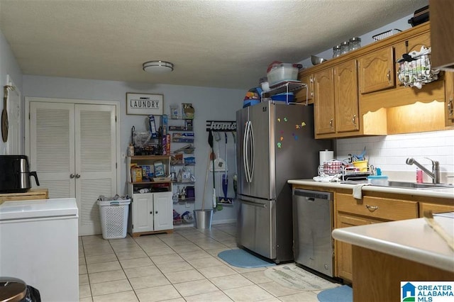 kitchen with tasteful backsplash, a textured ceiling, stainless steel appliances, sink, and light tile patterned floors