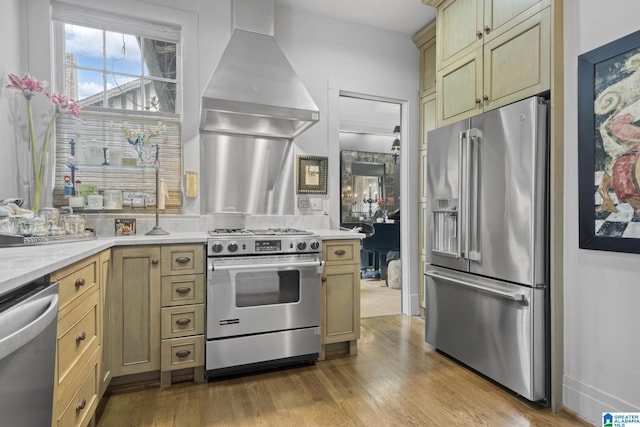 kitchen featuring light wood-type flooring, wall chimney range hood, and high end appliances