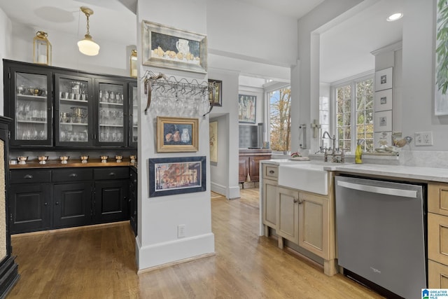 kitchen with dishwasher, hanging light fixtures, light wood-type flooring, and sink