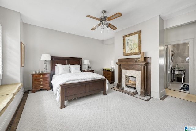 carpeted bedroom featuring a high end fireplace and ceiling fan