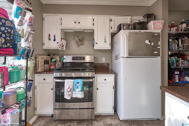 kitchen featuring stainless steel gas range oven, white cabinetry, and white refrigerator