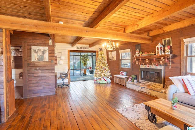 living room featuring beam ceiling, hardwood / wood-style flooring, a glass covered fireplace, wood walls, and wood ceiling