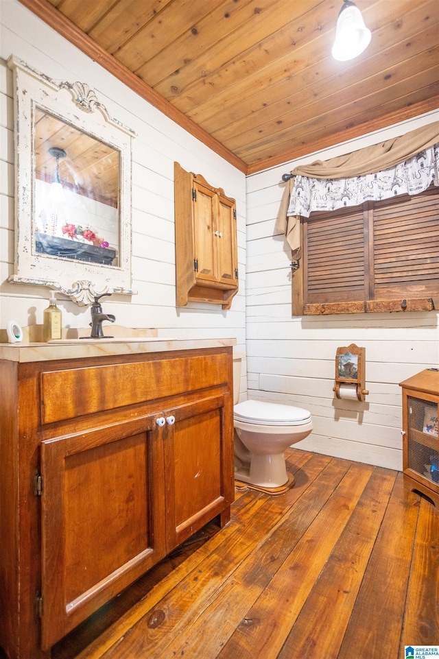 bathroom featuring wood walls, hardwood / wood-style floors, toilet, vanity, and wood ceiling