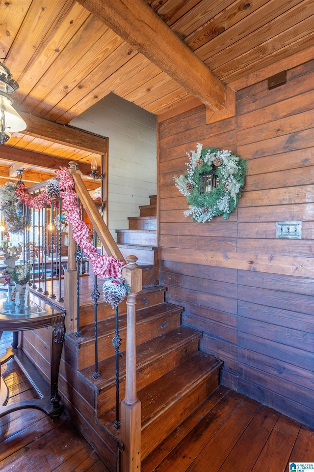 stairs featuring beam ceiling, wood ceiling, and wood-type flooring