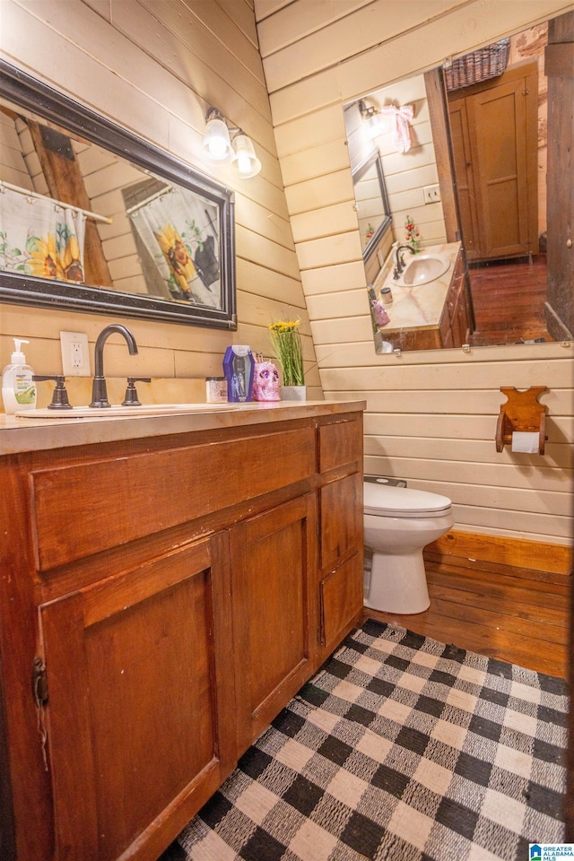 bathroom featuring wood-type flooring, vanity, toilet, and wood walls