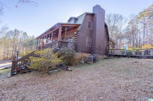 view of property exterior featuring a gambrel roof, log exterior, a wooden deck, cooling unit, and metal roof