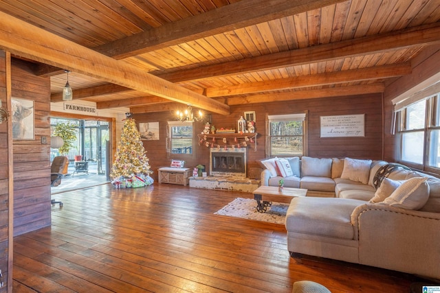 living room featuring a stone fireplace, a healthy amount of sunlight, and wood walls