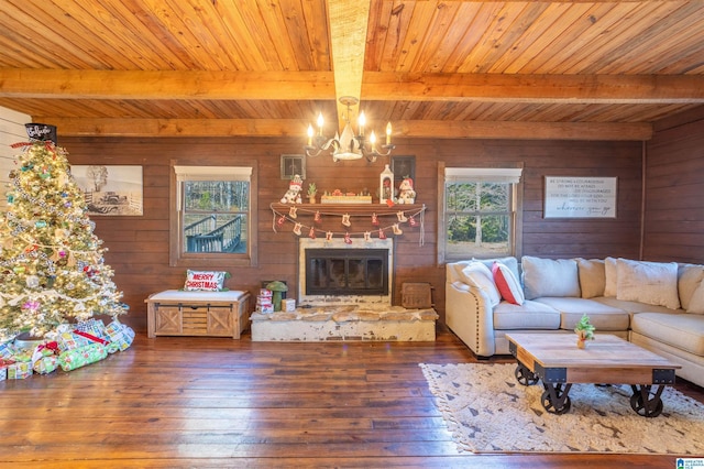 living room with a fireplace, a chandelier, beamed ceiling, dark hardwood / wood-style floors, and wood walls