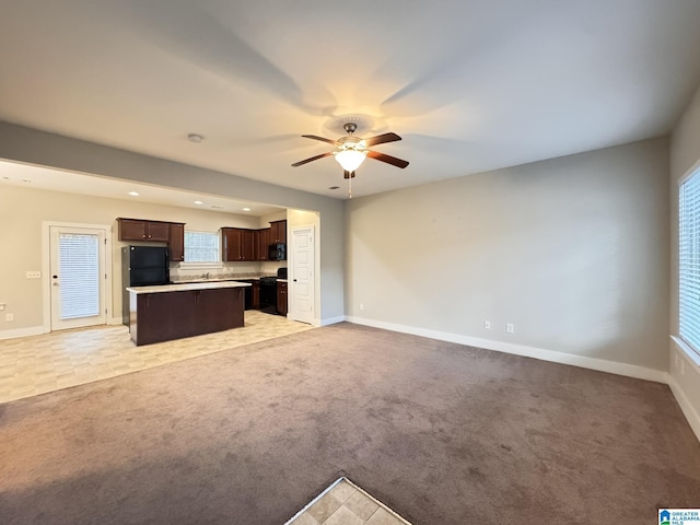 unfurnished living room featuring light carpet and ceiling fan