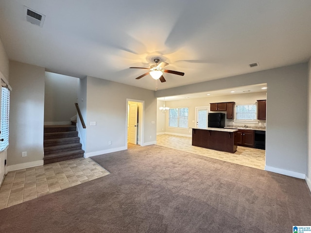 unfurnished living room with ceiling fan with notable chandelier and light colored carpet