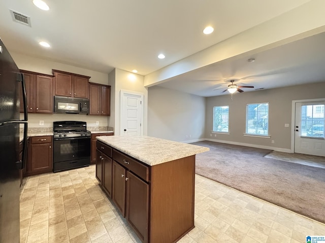 kitchen featuring a center island, black appliances, ceiling fan, light colored carpet, and dark brown cabinetry