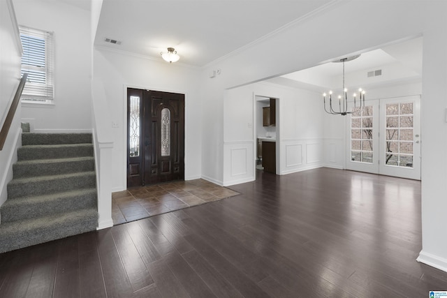 entryway with crown molding, dark wood-type flooring, and a notable chandelier