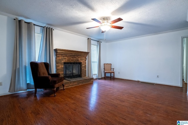 unfurnished room with crown molding, ceiling fan, a fireplace, a textured ceiling, and dark hardwood / wood-style flooring