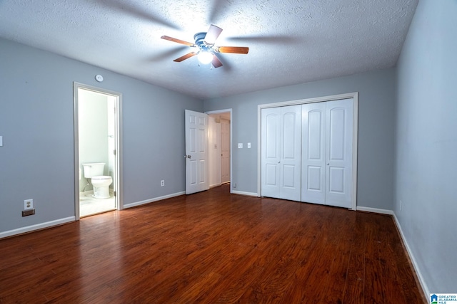 unfurnished bedroom featuring ceiling fan, dark hardwood / wood-style floors, a textured ceiling, connected bathroom, and a closet