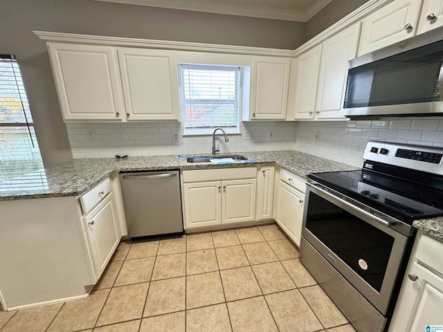 kitchen with light stone countertops, white cabinetry, sink, stainless steel appliances, and light tile patterned floors