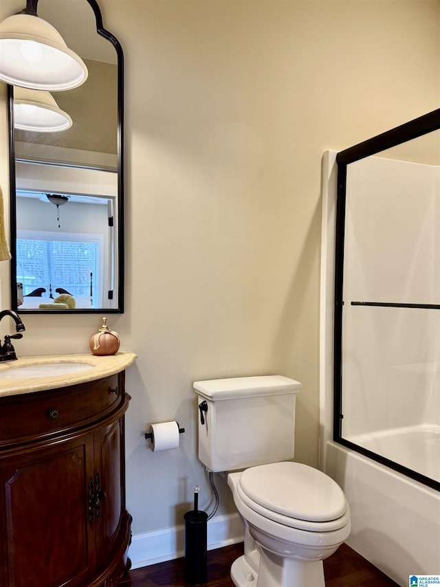 full bathroom featuring shower / bath combination with glass door, hardwood / wood-style floors, vanity, and toilet