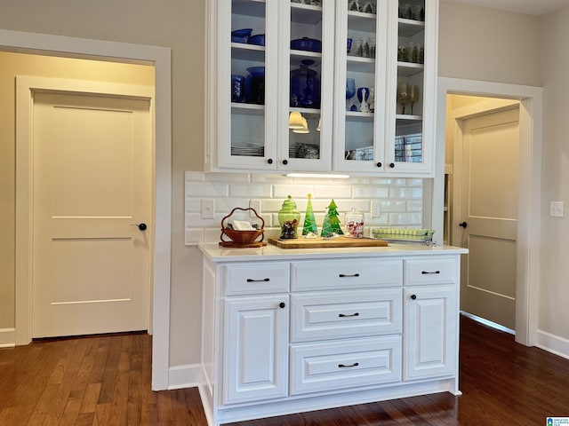 bar with decorative backsplash, white cabinetry, and dark hardwood / wood-style flooring