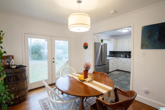 dining space with dark hardwood / wood-style floors, ornamental molding, a wealth of natural light, and french doors