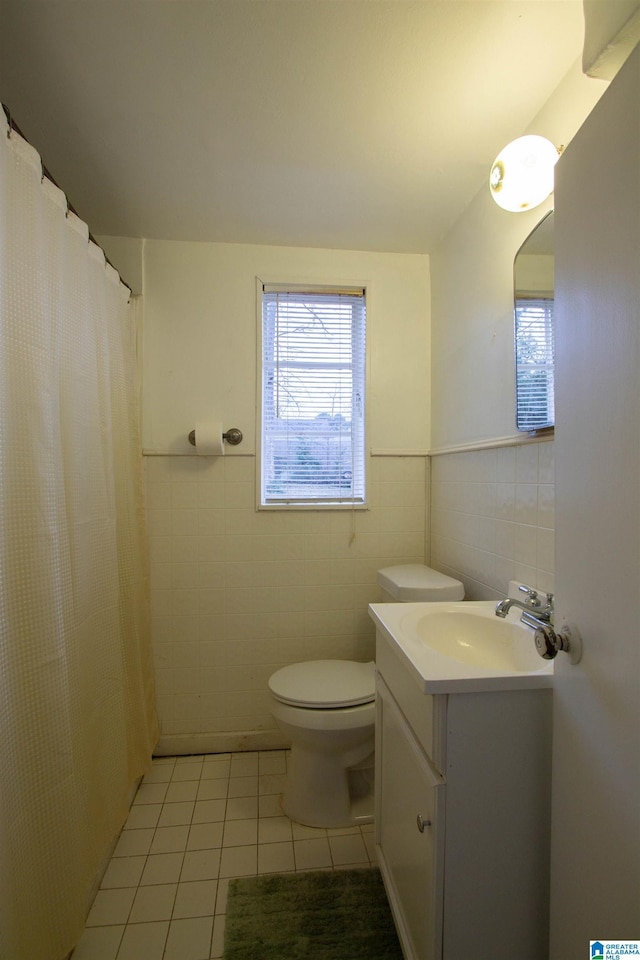 bathroom featuring tile patterned flooring, vanity, toilet, and tile walls