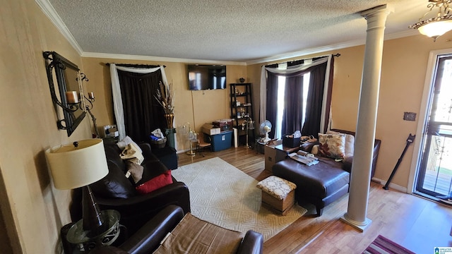 living room with decorative columns, hardwood / wood-style floors, a textured ceiling, and ornamental molding