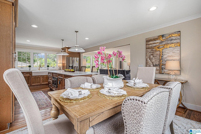 dining space with hardwood / wood-style floors, crown molding, and sink