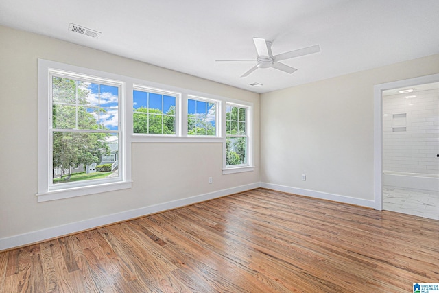 empty room featuring hardwood / wood-style flooring, ceiling fan, and a healthy amount of sunlight