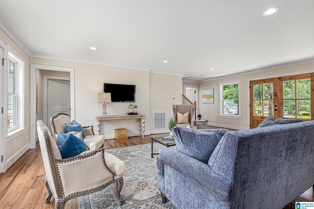 living room with light hardwood / wood-style floors, ornamental molding, and french doors