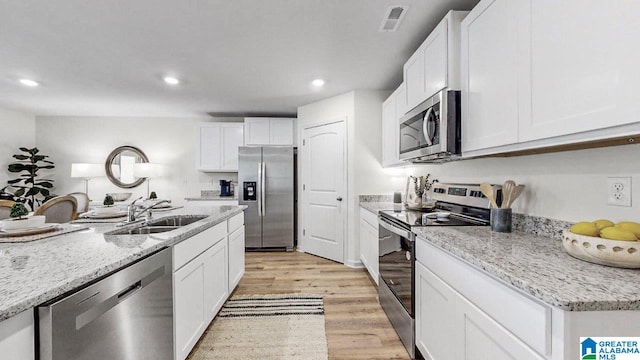 kitchen with white cabinets, appliances with stainless steel finishes, light wood-type flooring, and sink