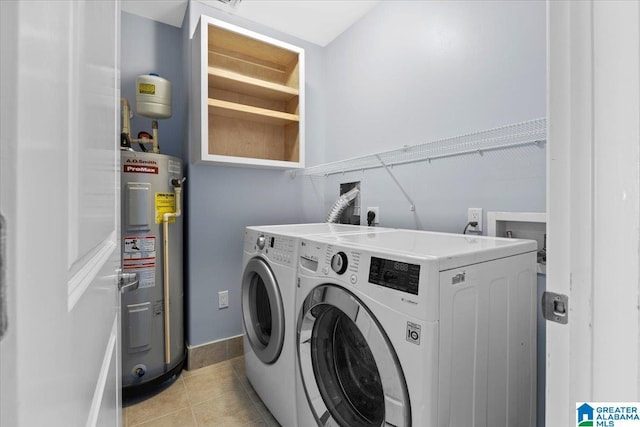 washroom featuring water heater, washing machine and dryer, and light tile patterned floors