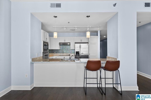 kitchen featuring white cabinets, kitchen peninsula, backsplash, stainless steel appliances, and light stone counters